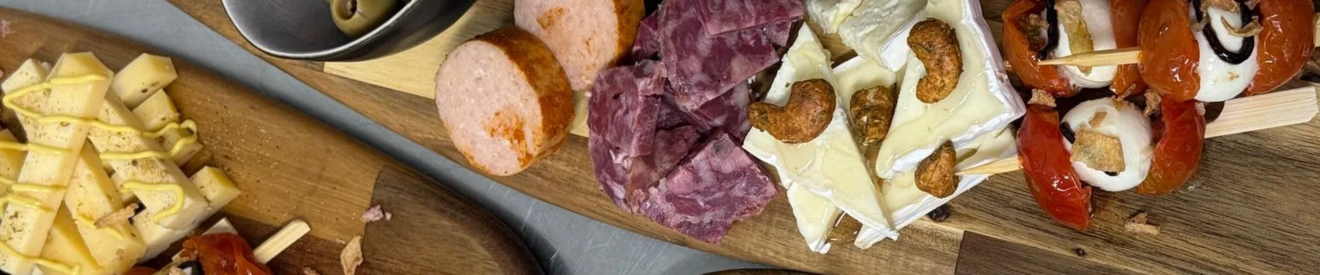 Houten plank met kaas, charcuterie en tomaat-mozzarellaspiesjes