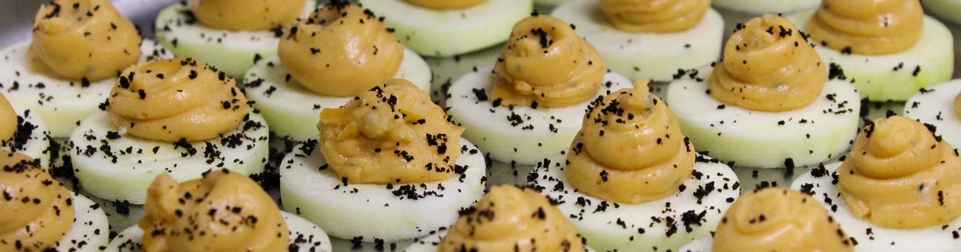 Komkommerhapjes met een romige mousse en zwarte crumble, geleverd op kantoor